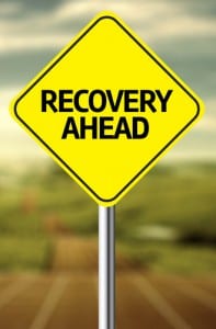Yellow road sign that states "RECOVERY AHEAD"