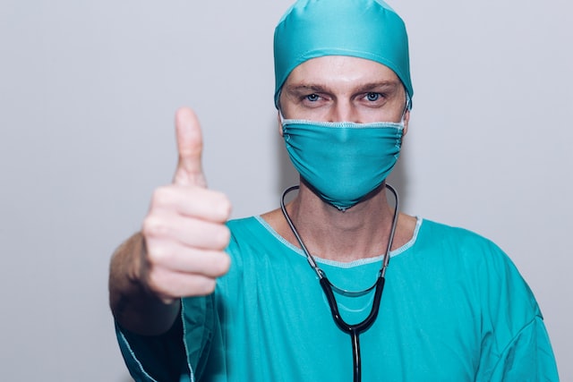 Doctor wearing scrubs and showing a thumbs up