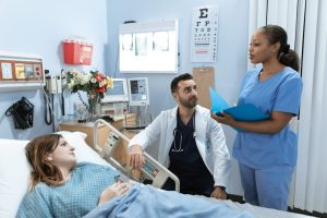 A woman lying in a hospital bed while talking to the nurse and the doctor.