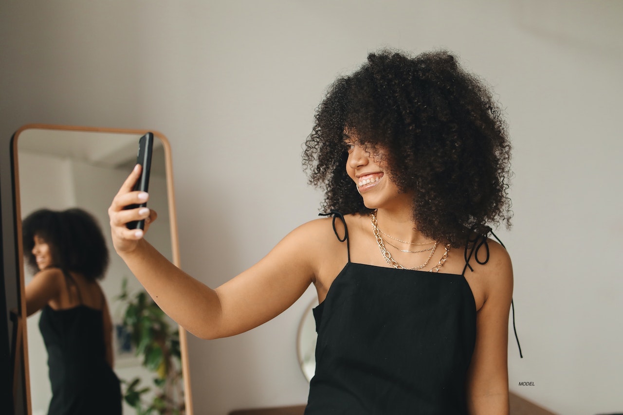 A woman smiling while looking at her phone.