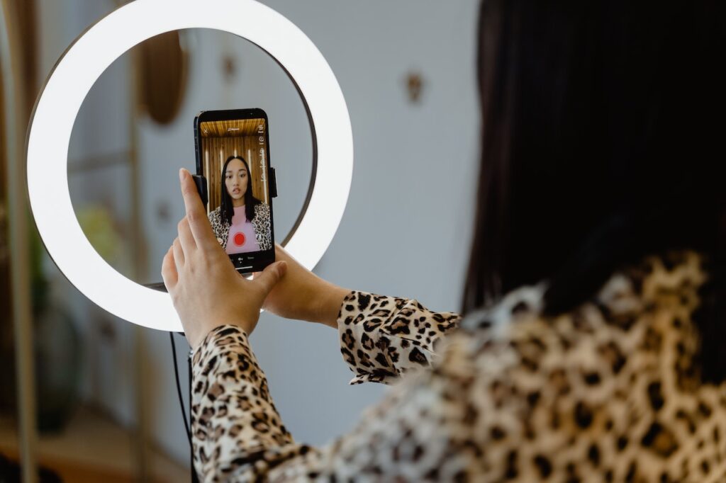 a woman taking selfie in front of a ring light.