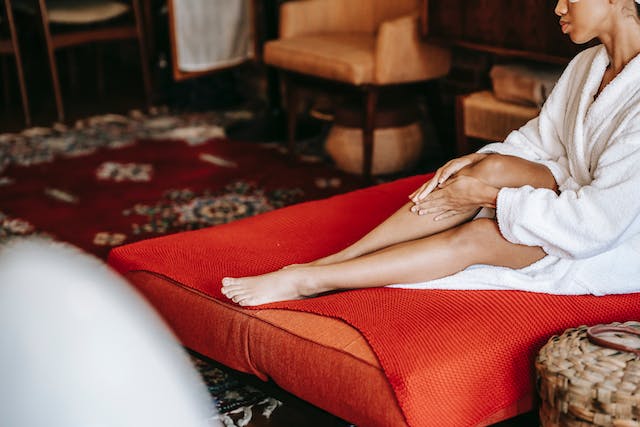 Woman putting a lotion on her legs to minimize scarring after plastic surgery