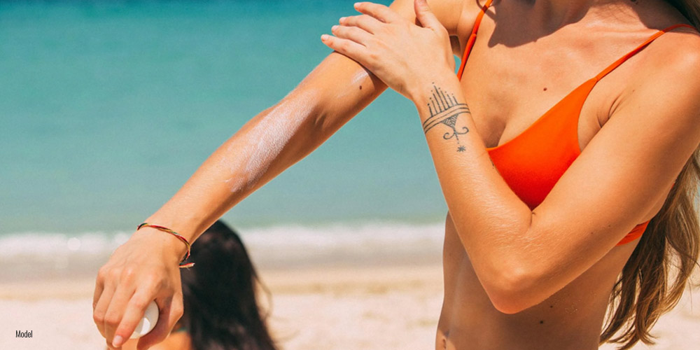 woman in bikini applying sunscreen lotion.