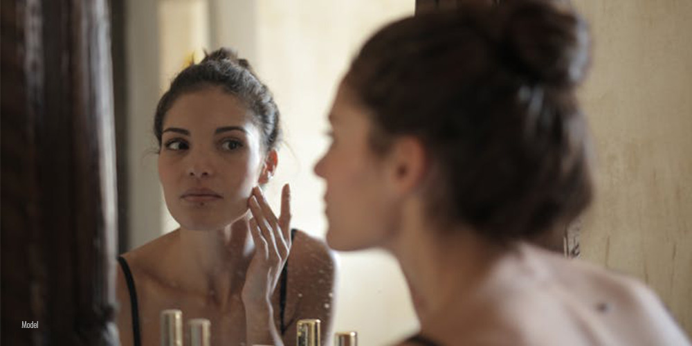 a woman checking her face in a mirror